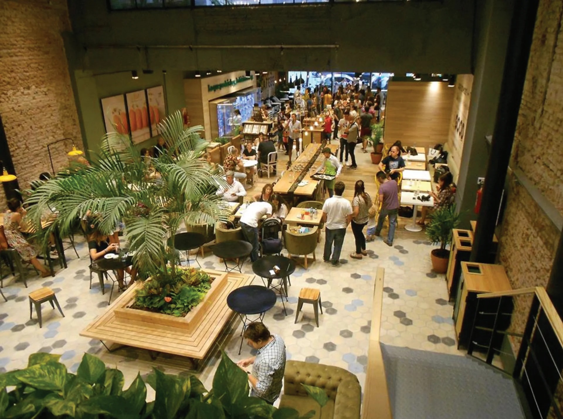 Green Eat aerial view of crowded flagship, tropical plants, hexagonal floor tiles