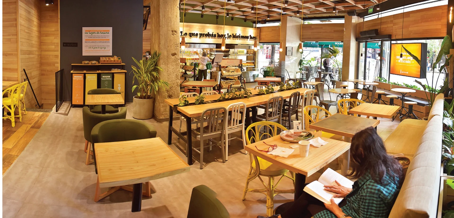 Green Eat interior, natural wood tables, greenery, warm pendant lighting