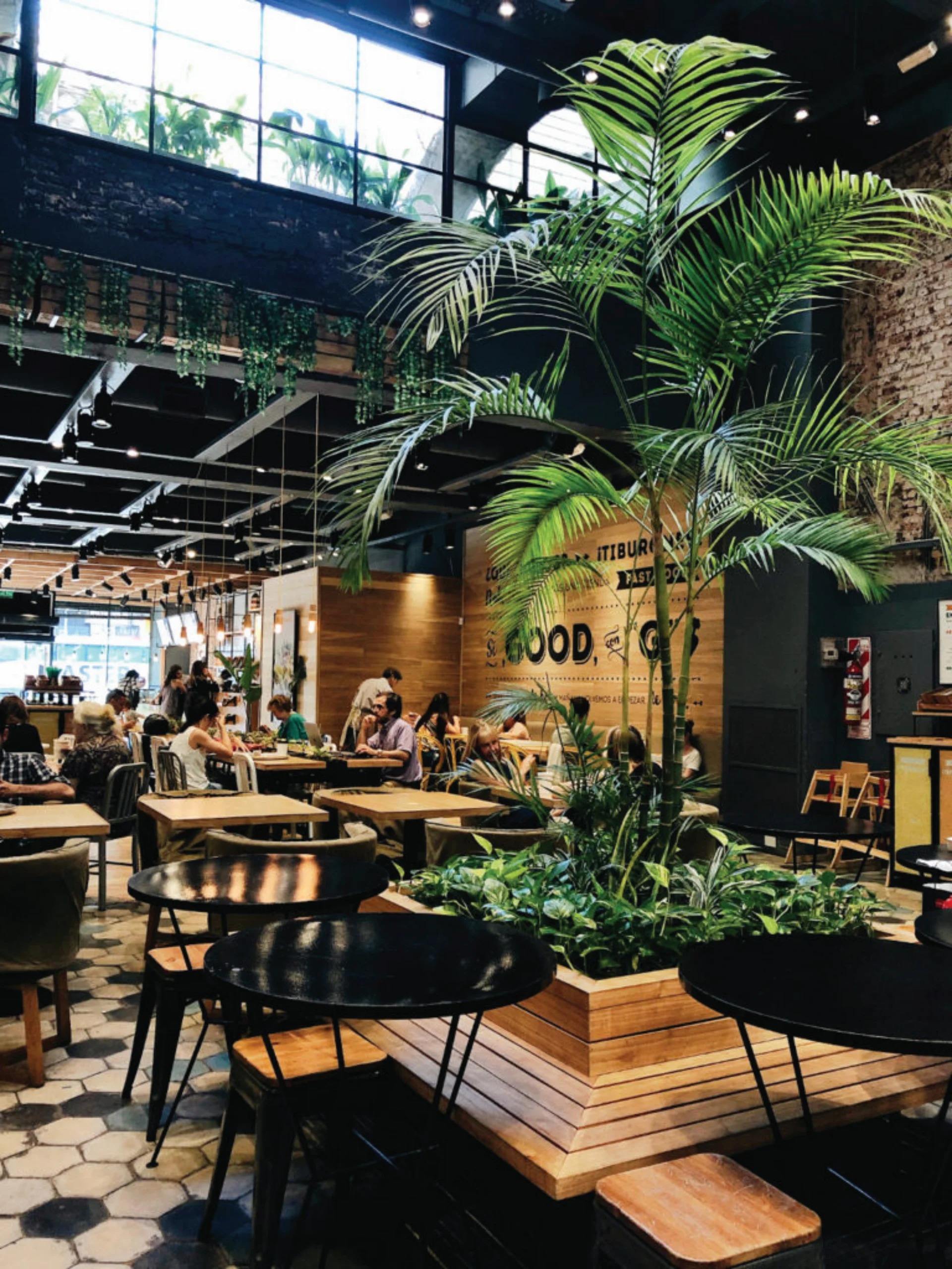 Green Eat large-format interior, tropical palms, wood panelling, communal dining