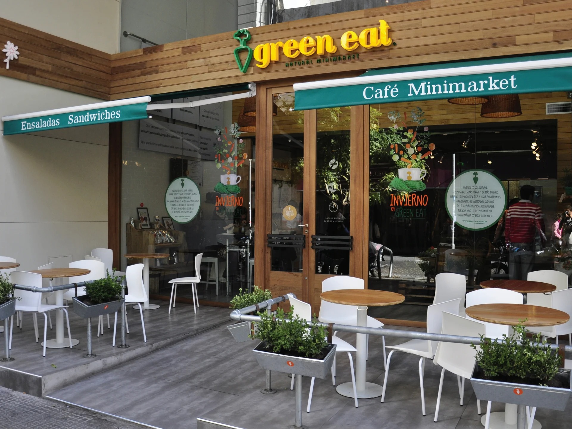 Green Eat café minimarket exterior, wood facade, teal awning, street terrace